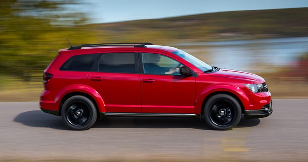 Image of a red 2019 Dodge Journey parked by a lake.