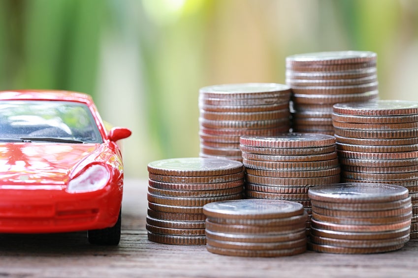 Image of a red toy car next to a stack of coins.