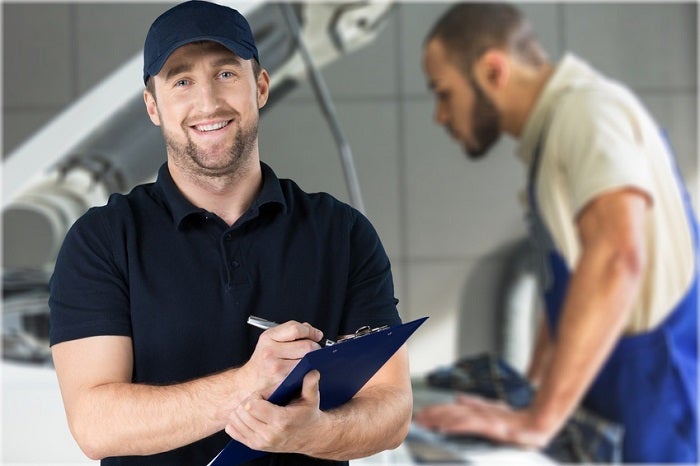 Image of a mechanic holding a clipboard in a work shop.
